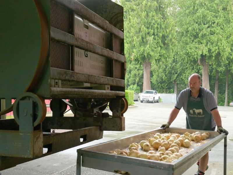 Man pushing onions on a tray.