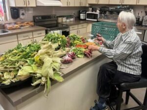 Volunteer trims wilted vegetables.