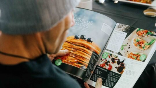 Over the shoulder of someone reading a recipe from Love Food Hate Waste.