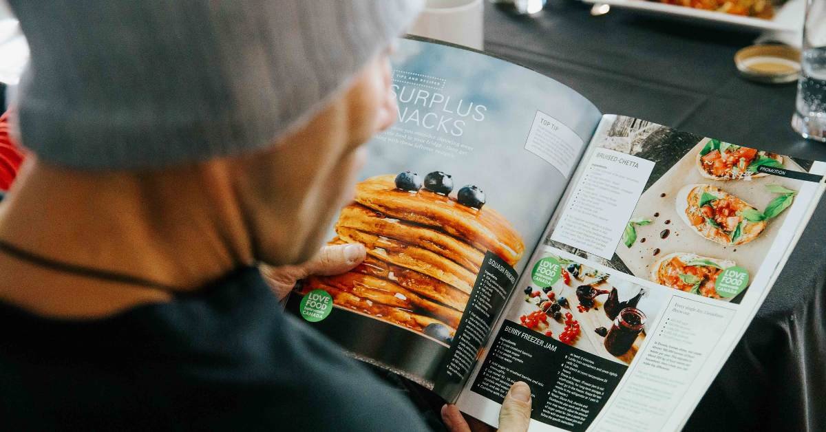 Over the shoulder of someone reading a recipe from Love Food Hate Waste.